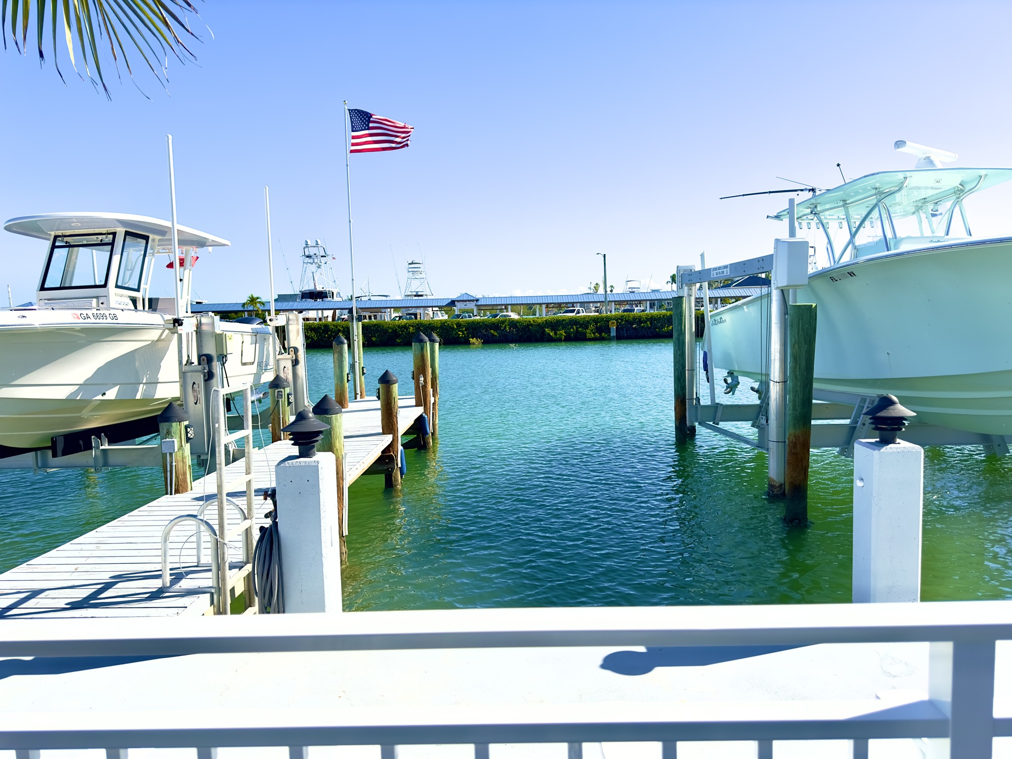 Boats docked at sunny marina with American flag