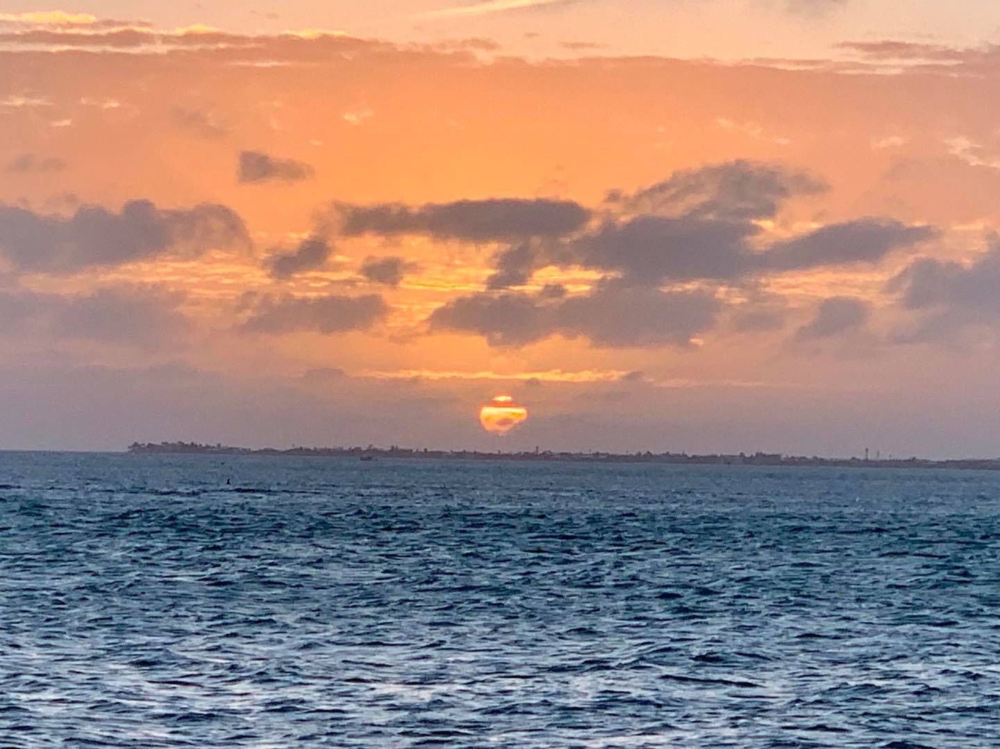 Orange sunset over ocean with distant coastline