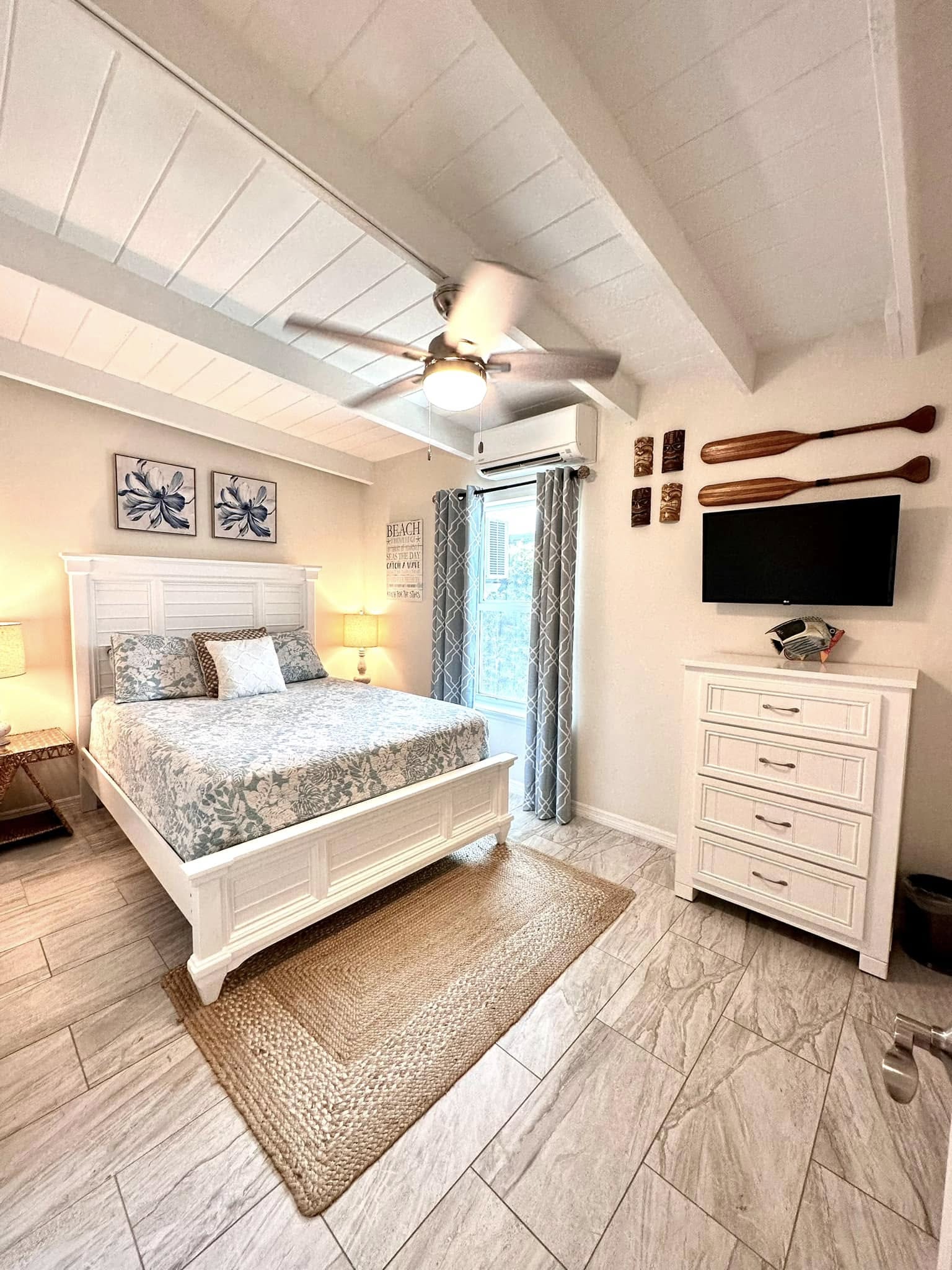 Bright coastal bedroom with white bed and dresser