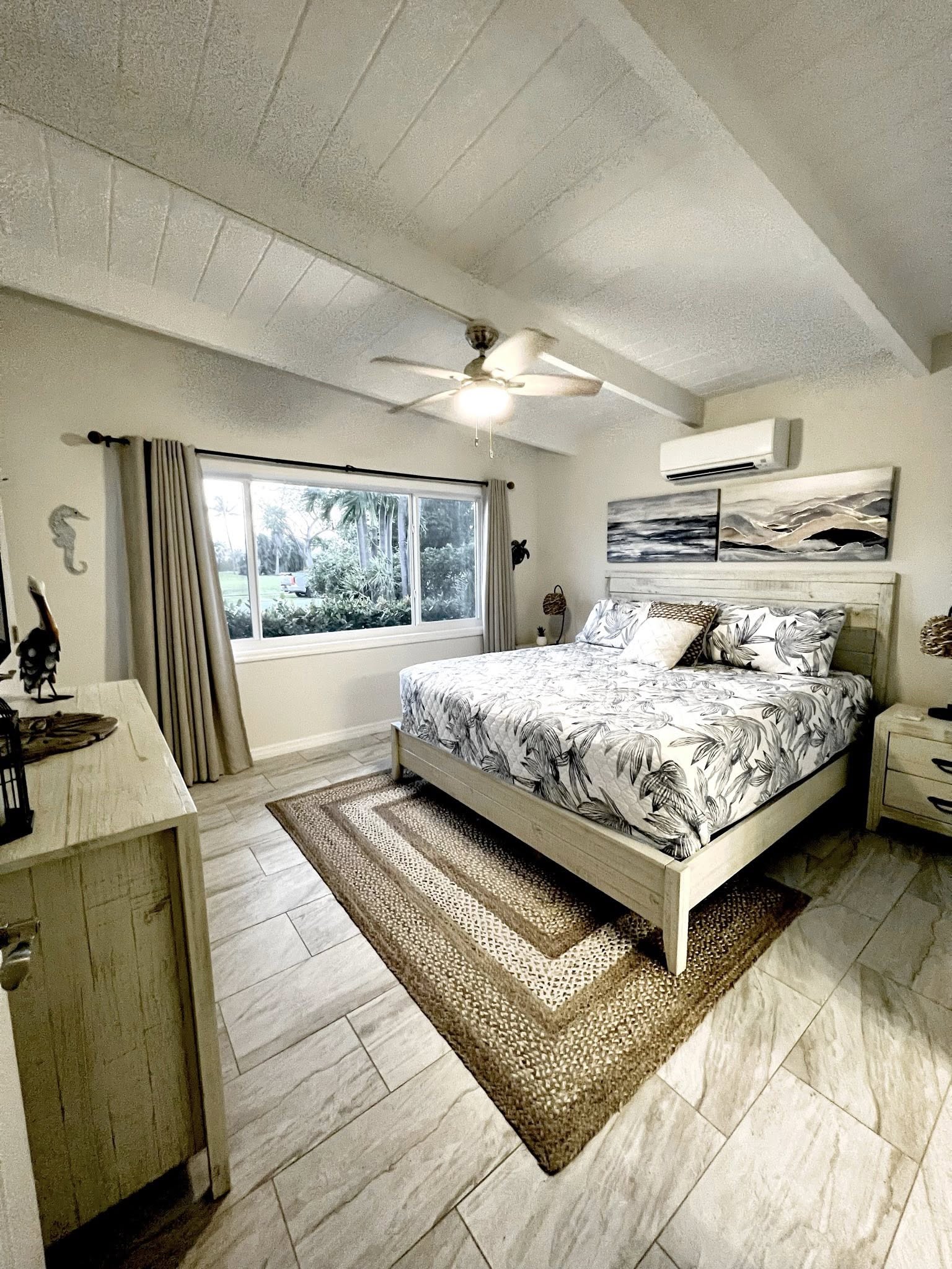 Bright coastal bedroom with king bed and window