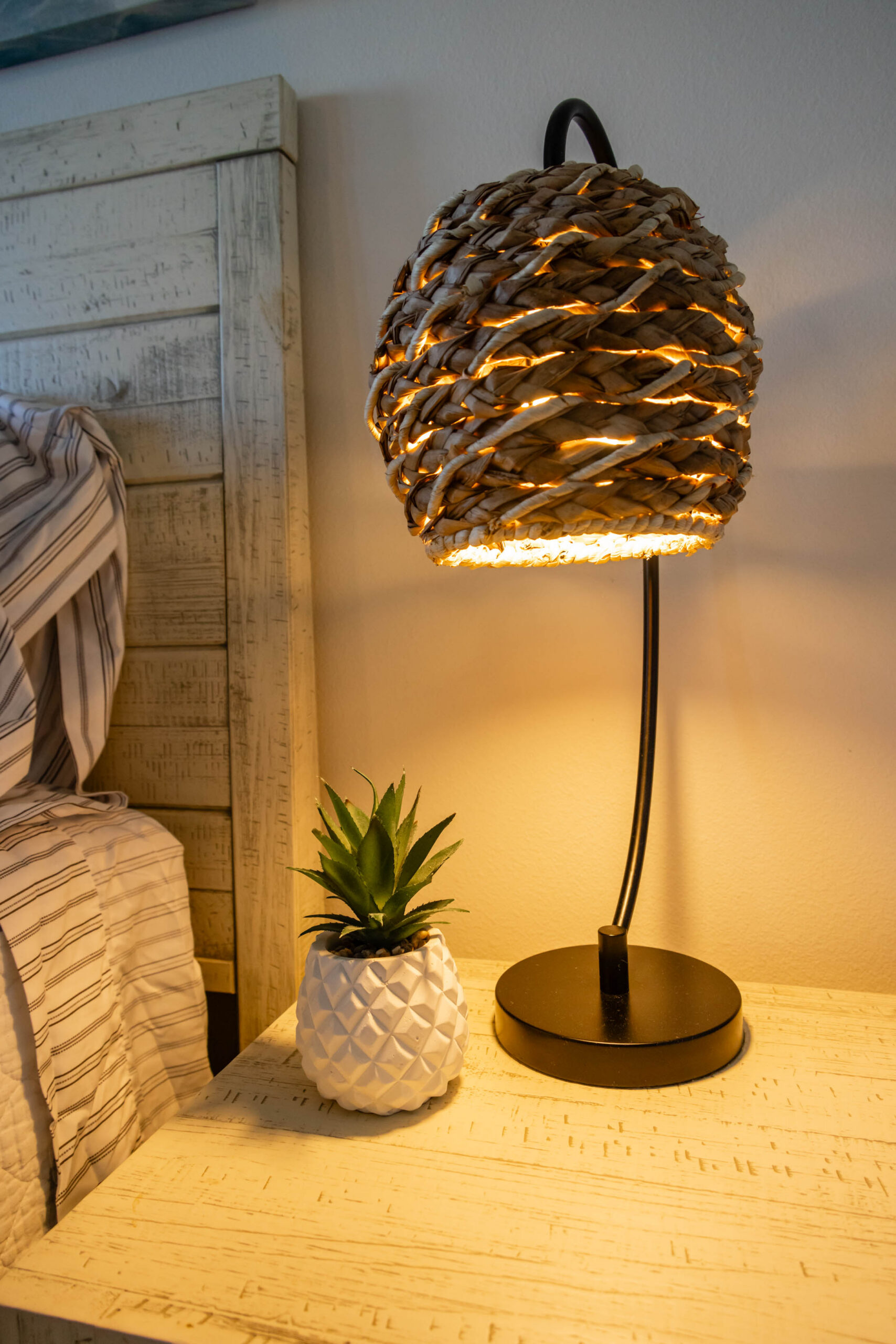 Woven rattan lamp and succulent on nightstand