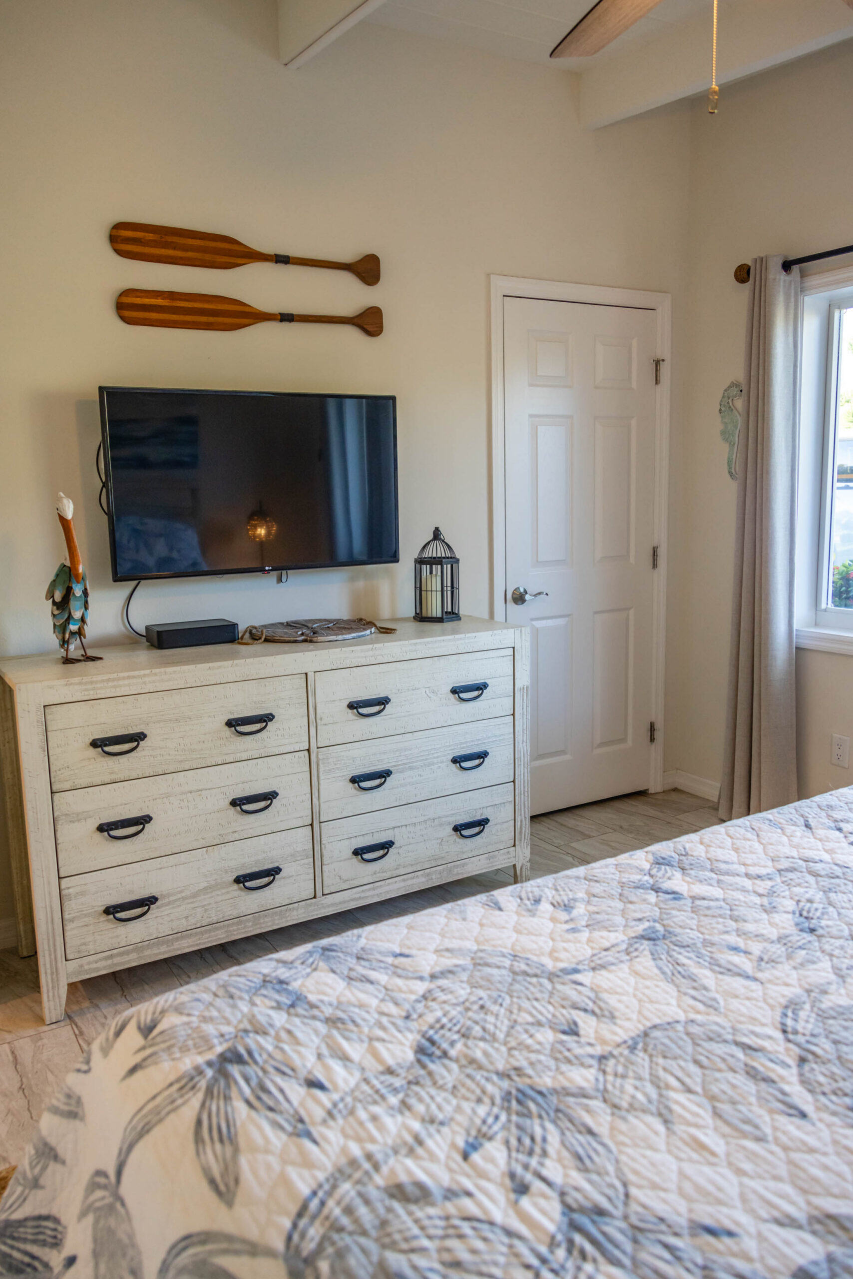Coastal bedroom with dresser, TV, wooden oars