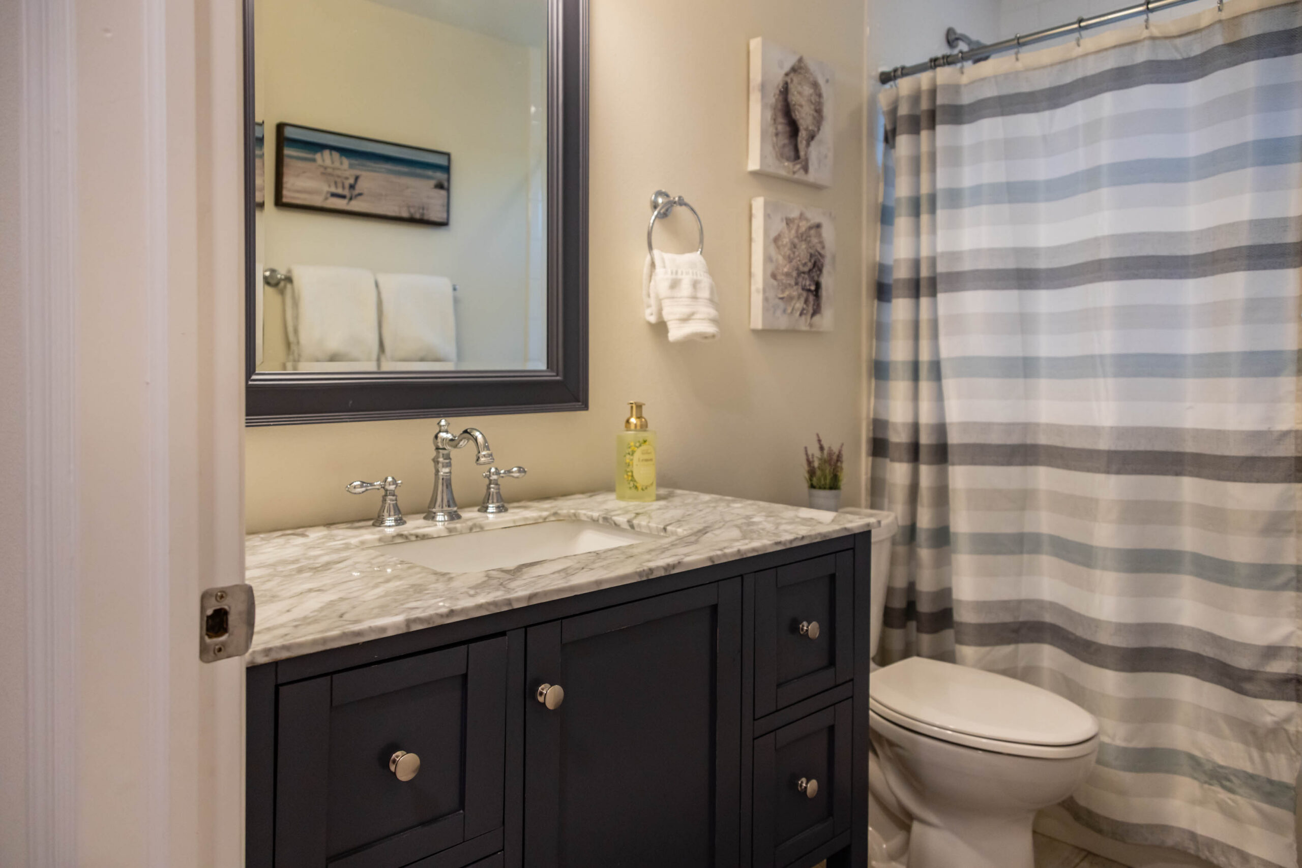 Bathroom vanity with marble countertop and striped curtain