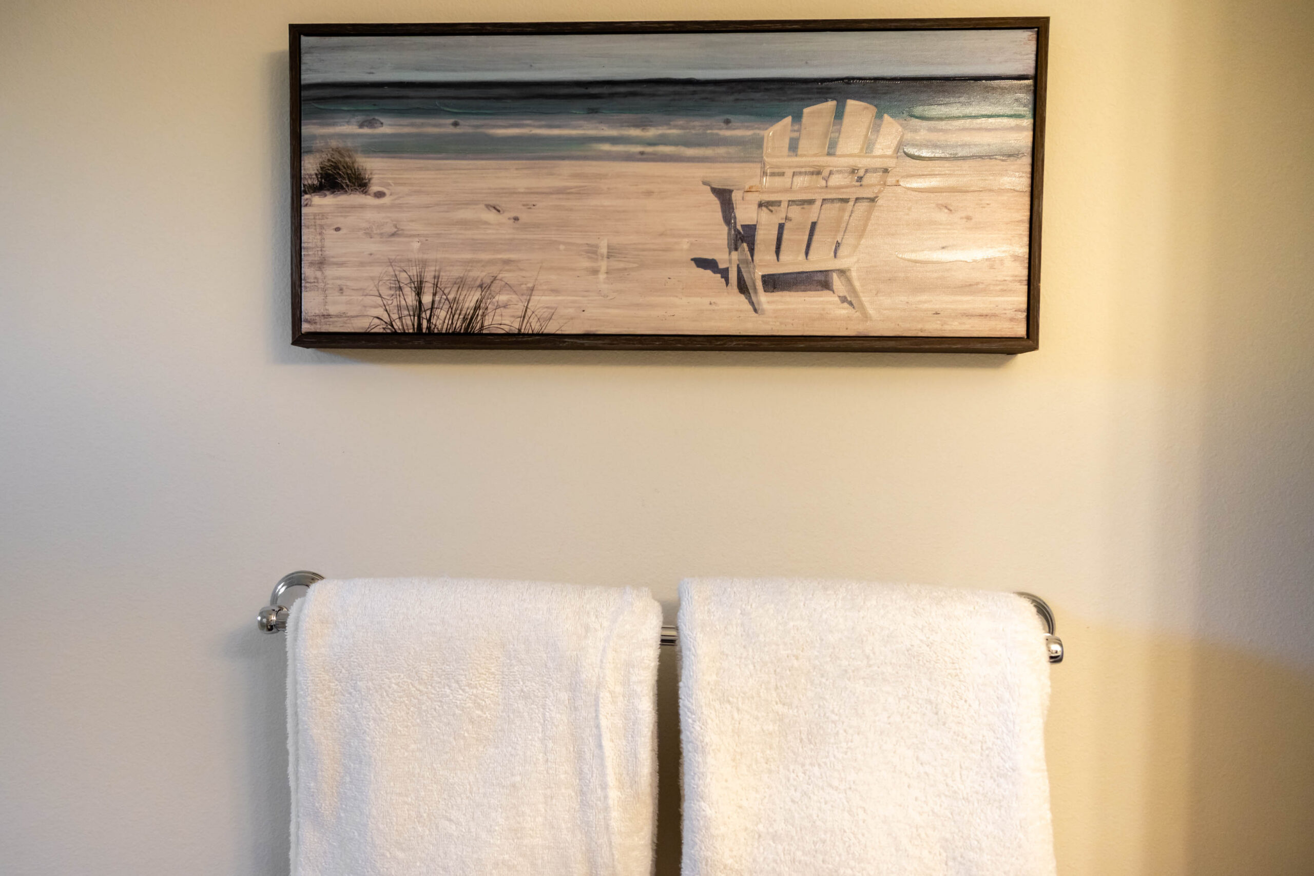 Framed beach artwork above two white towels