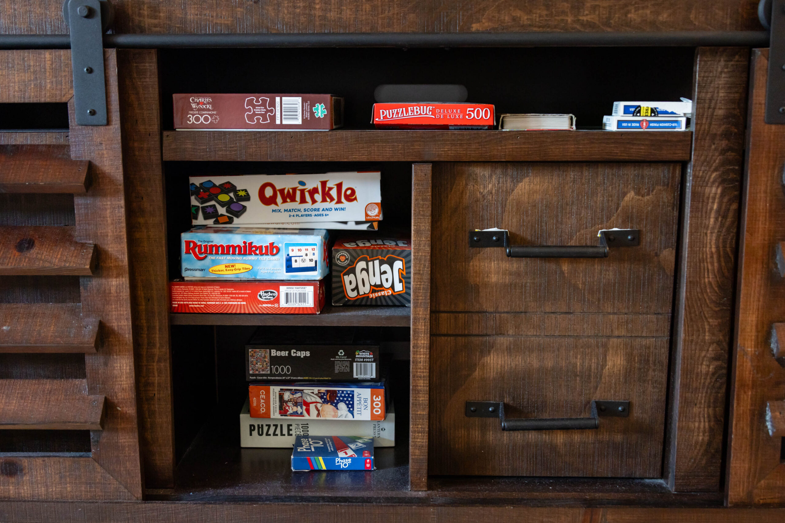 Assorted board games and puzzles in wooden cabinet