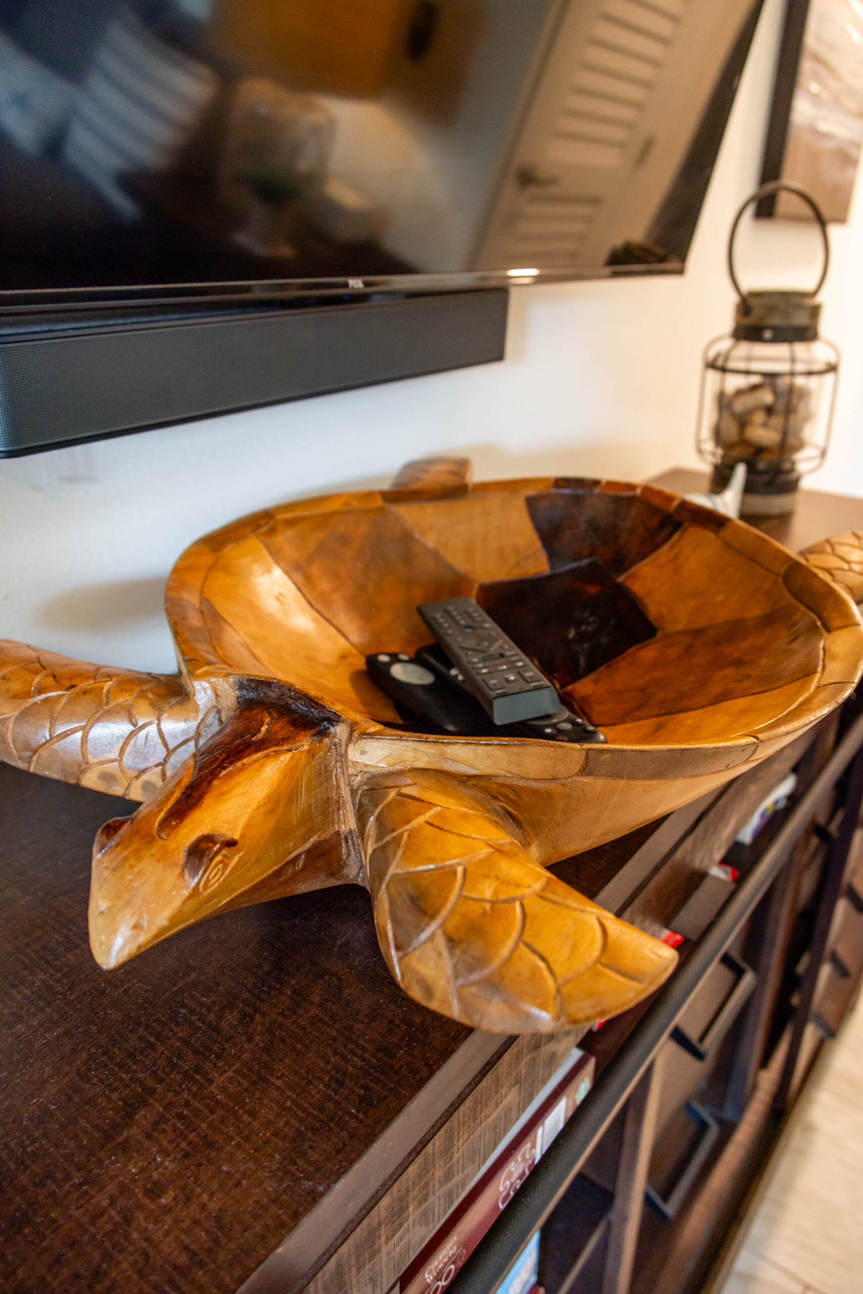 Carved wooden turtle bowl holding TV remotes