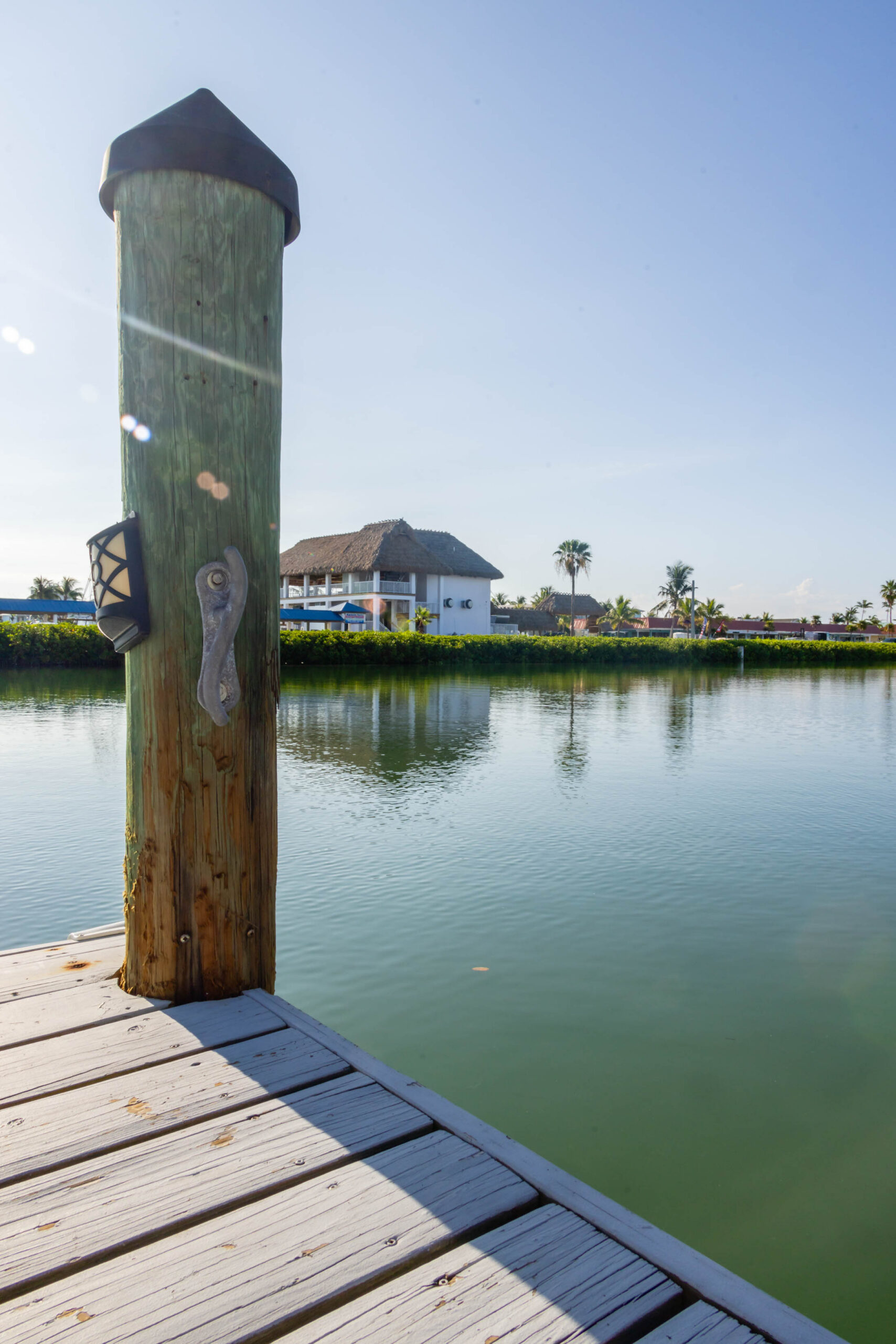 Dock post on sunny canal with waterfront house