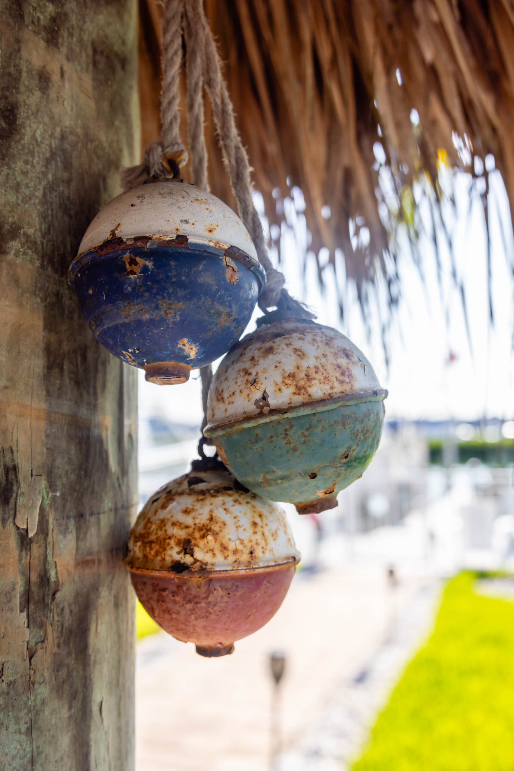 Three weathered colorful fishing buoys hanging on post