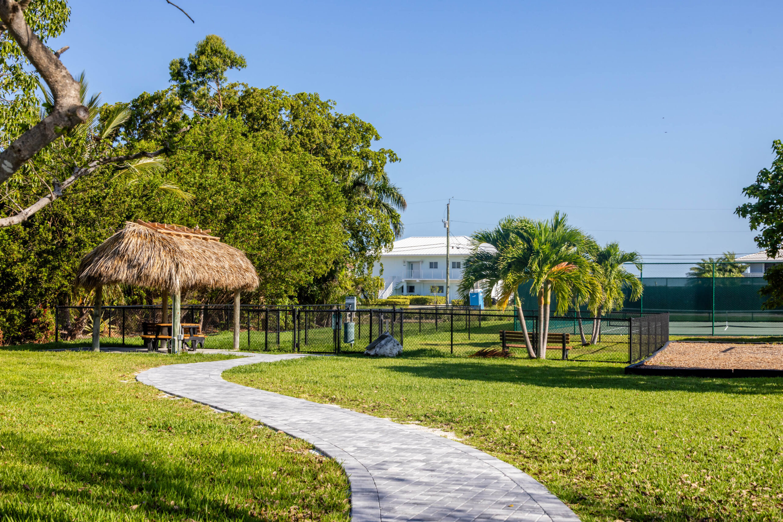 Curving paved path leading to tiki hut gazebo