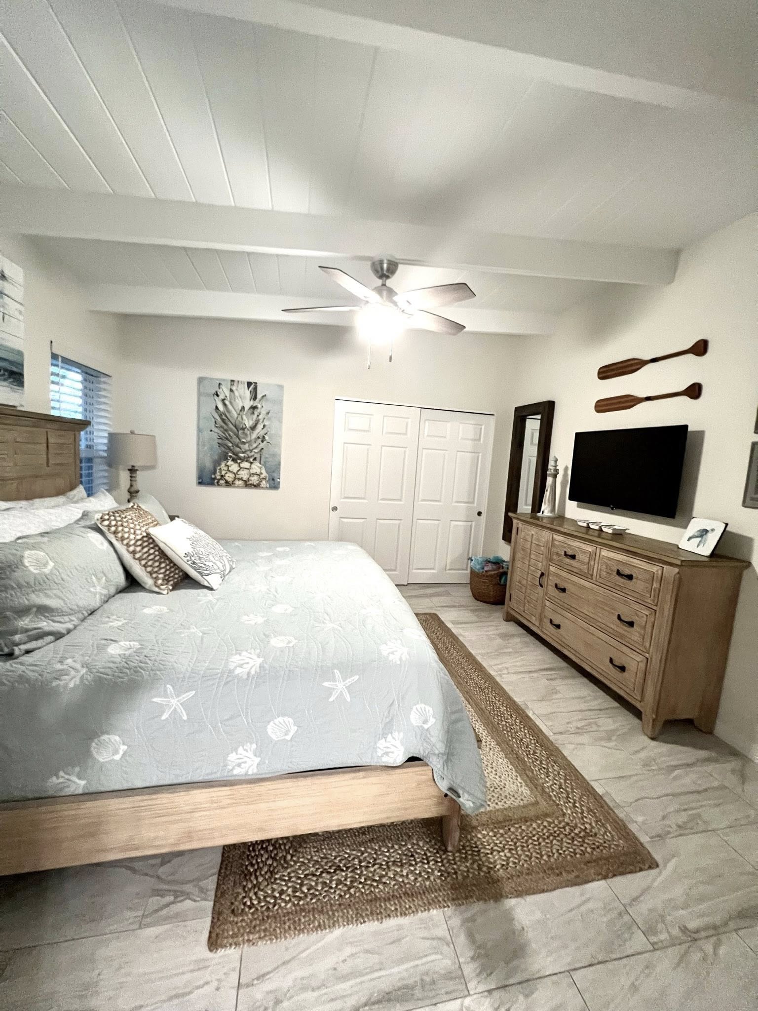 Coastal bedroom with bed, dresser, ceiling fan