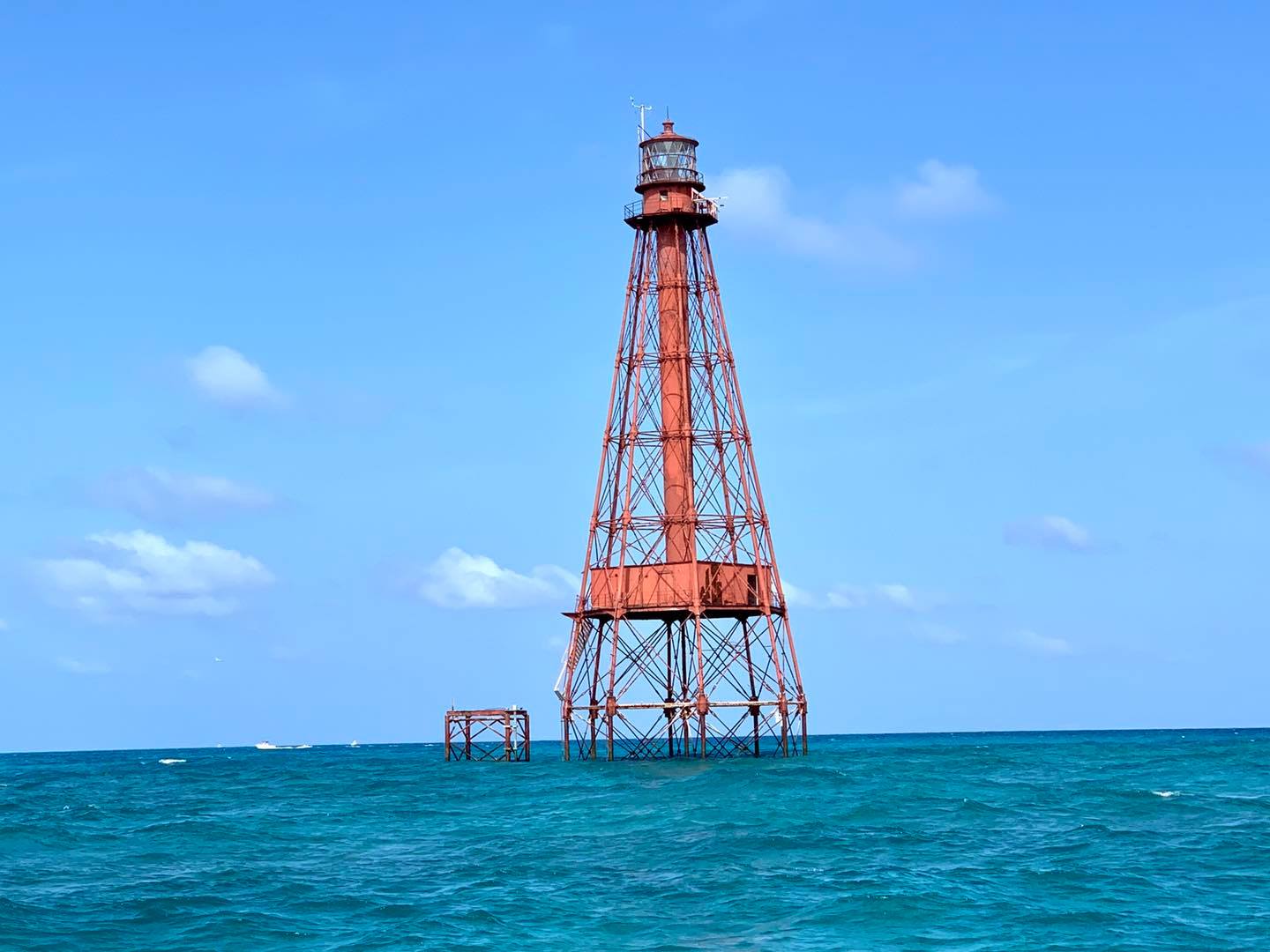 Red skeletal offshore lighthouse in turquoise sea