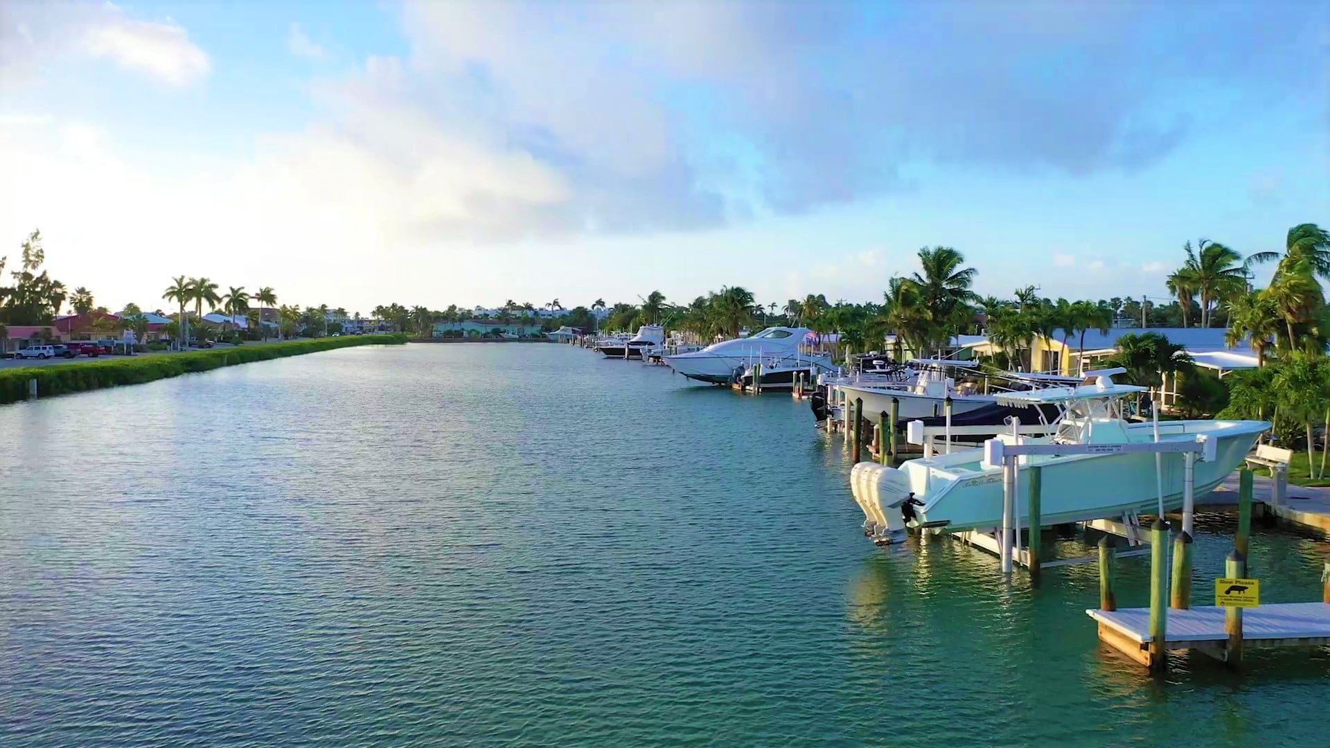 Tropical residential canal with boats docked.