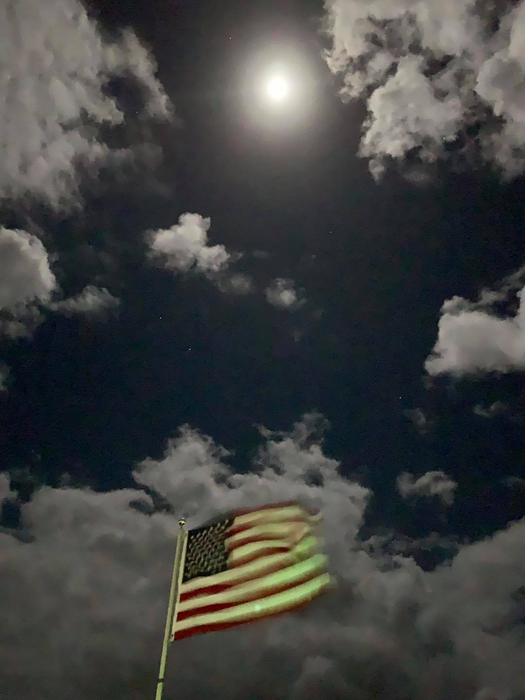 American flag under moonlit cloudy night sky