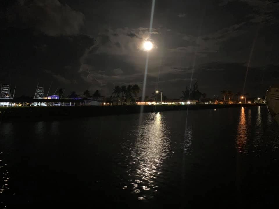 Full moon reflecting over marina water at night