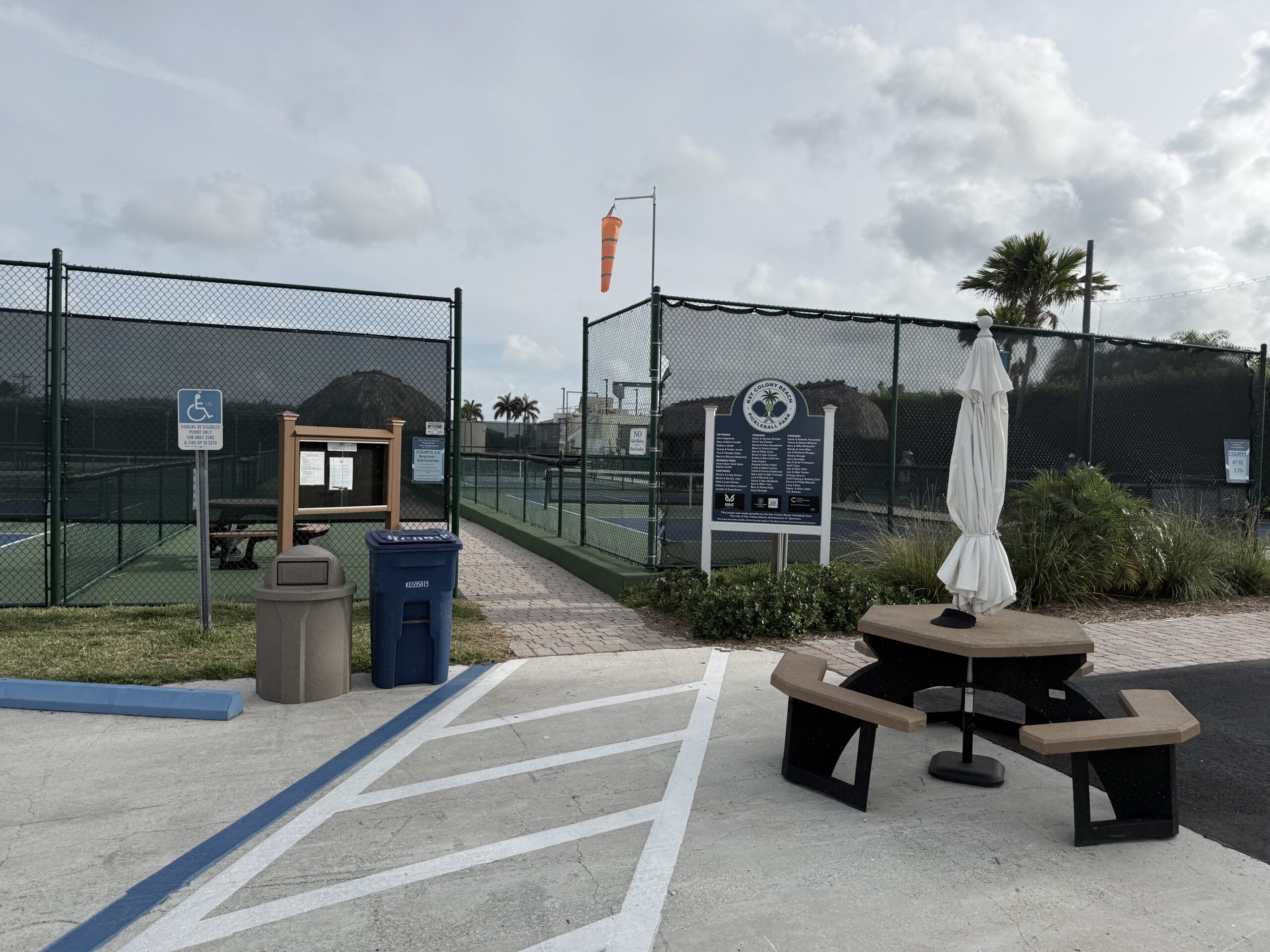 Outdoor tennis courts with picnic table and windsock