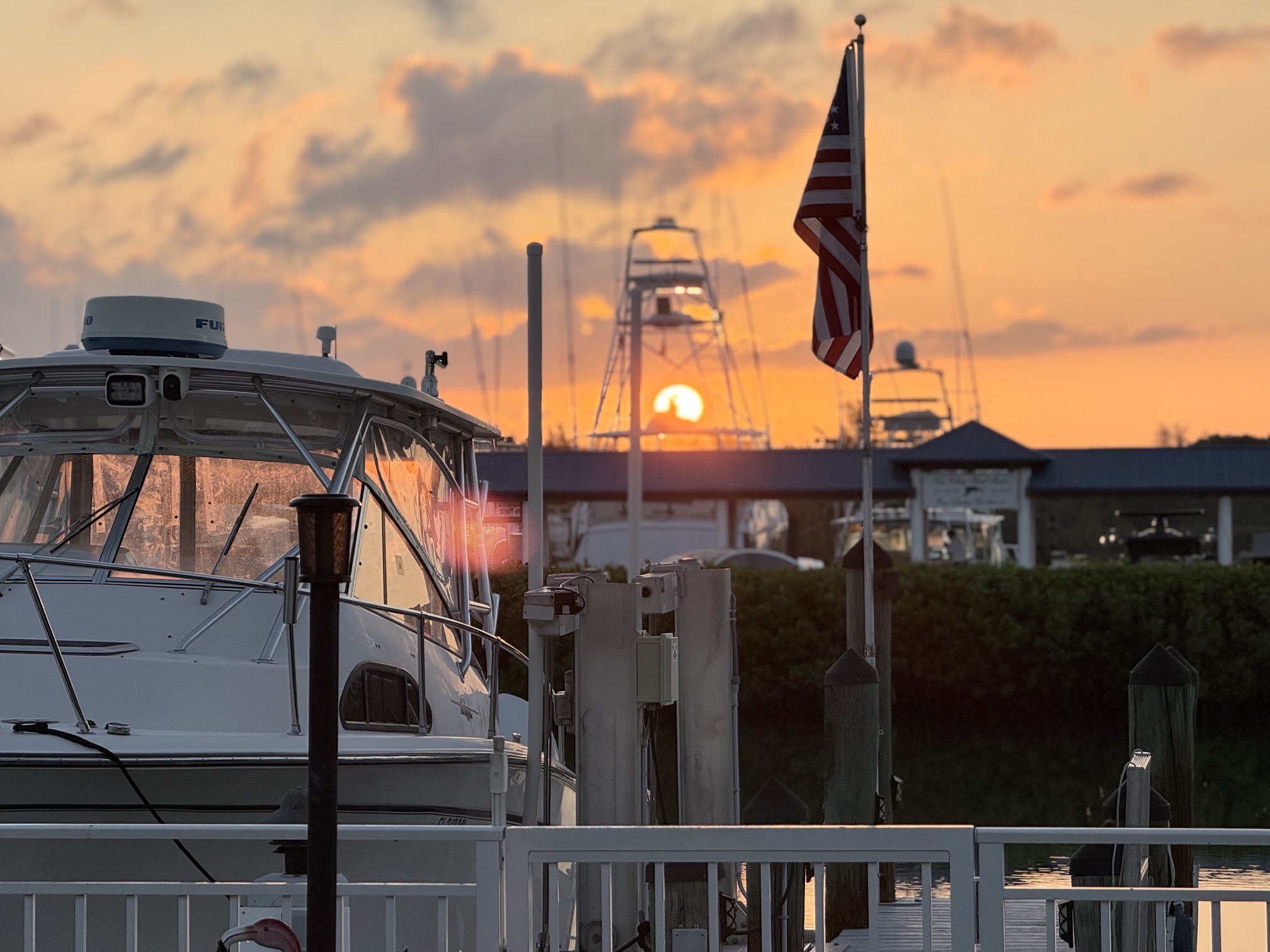 Sunset over marina with docked boat and flag